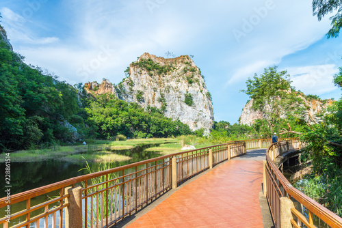 Beautiful rock mountain or hill landscape with clear lake and long walkway in sunny day blue sky. Asia travel destination concept  Ratchaburi Thailand. Traveling on holiday vacation summer season.