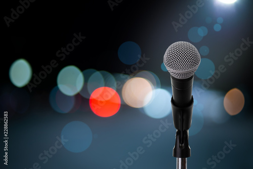 Microphone on stage ..Close up of microphone setting on stand with colorful light bokeh background in concert hall ,showbiz concept.