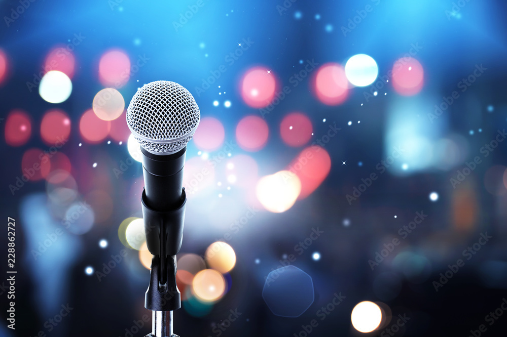Fototapeta premium Mikrofon na scenie .. Zbliżenie ustawienia mikrofonu na stojaku z kolorowym światłem bokeh w sali koncertowej, koncepcja showbiznesu.