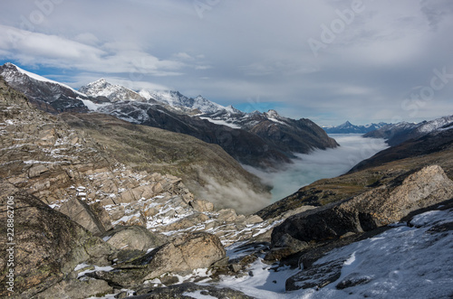 View to covered by clouds and mist  Stausee lake near Saas Fee in the southern Swiss Alps from Monte Moro pass  Italy