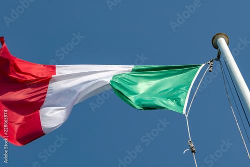 Bandiera Italiana sventolante issata su un pennone, con il tricolore photo