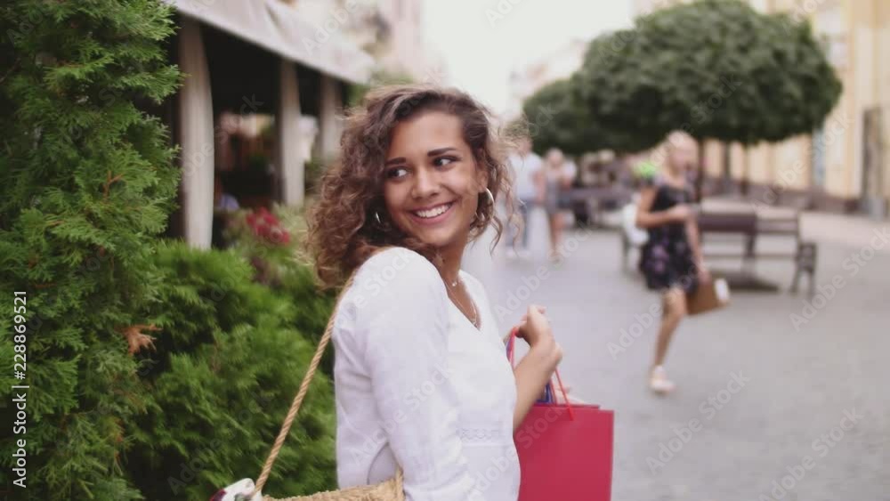 Beautiful woman holding shopping bags and smiling - outdoors