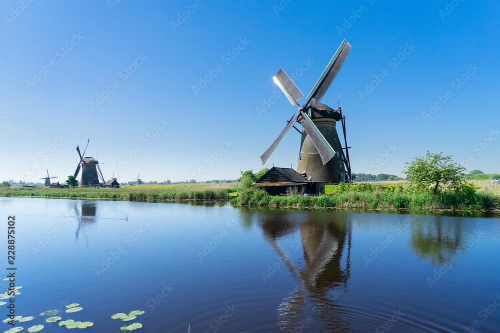 traditional dutch windmill with reflection at water, Kinderdijk at summer day, Netherland