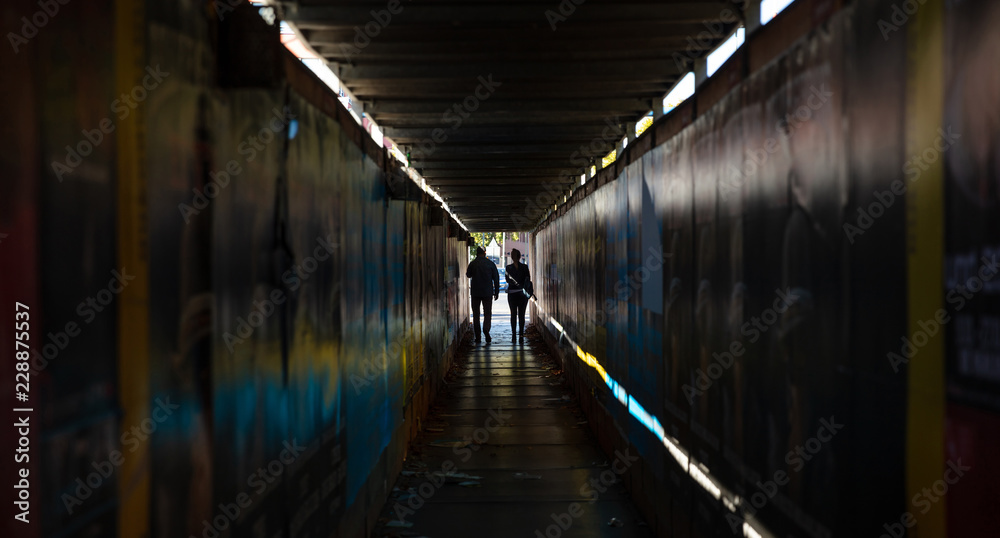 The Light at the End of the Tunnel. Young couple walking in a dark protective passage
