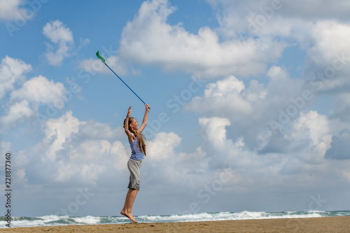 girl in a in striped t-shirt on the sea catches clouds by a net on a sunny day
