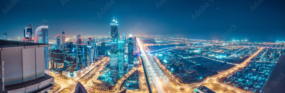 Spectacular urban skyline with colourful city illuminations. Aerial view on highways and skyscrapers of Dubai, United Arab Emirates.