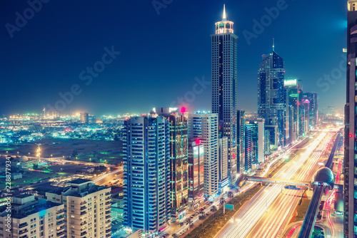 Spectacular urban skyline with colourful city illuminations. Aerial view on highways and skyscrapers of Dubai  United Arab Emirates.