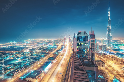 Scenic nighttime skyline of big cmodern city with illuminated skyscrapers. Aerial perspective of downtown Dubai, UAE. Multicolored travel background.