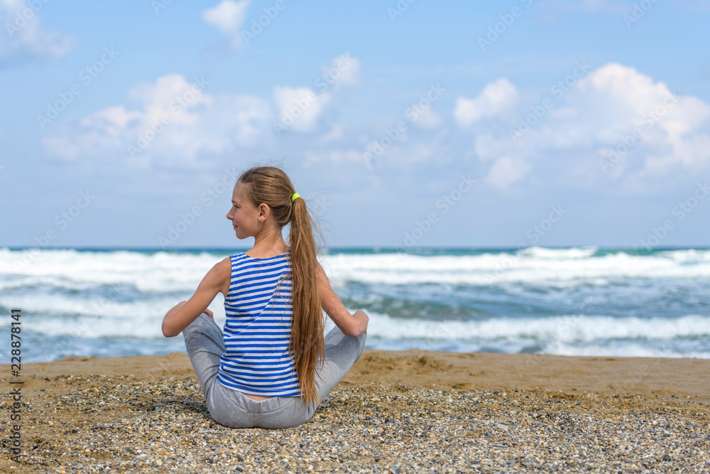 young girl in striped t-shirt is sitting on the beach and watching at the sea young girl in striped t-shirt is sitting on the beach and watching at the sea
