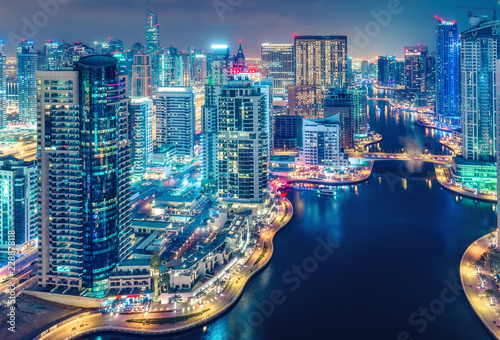 Scenic nighttime skyline of big modern city with illuminated skyscrapers. Aerial view of Dubai Marina, UAE. Multicolored travel background.