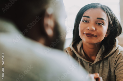 Calm pretty dark haired lady looking attentively at her beloved man while listening to him