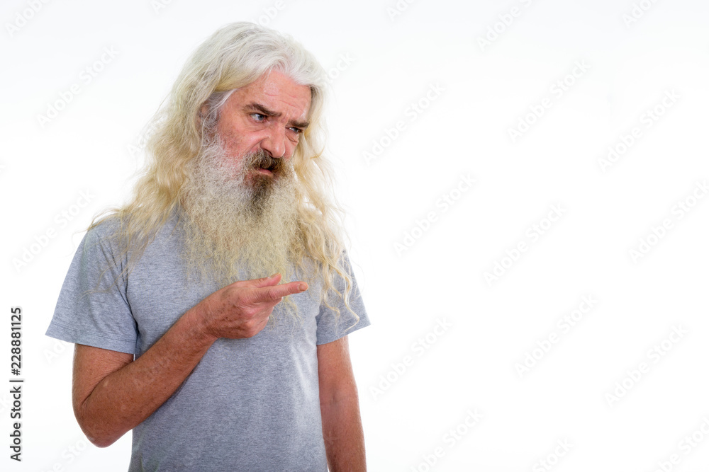 Studio shot of disgusted senior bearded man looking and pointing Studio shot of disgusted senior bearded man looking and pointing