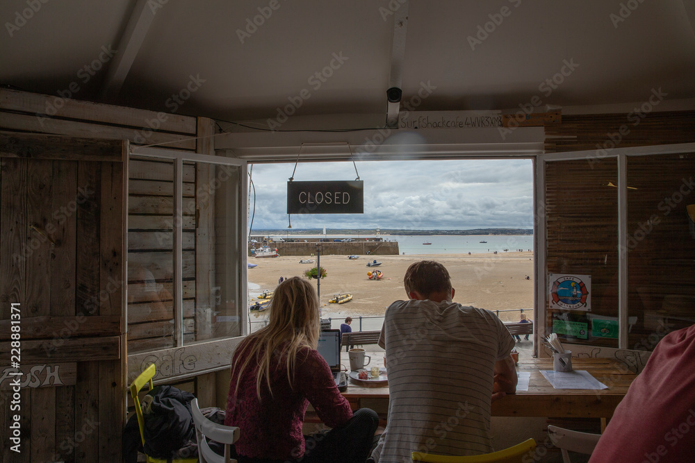 St. Ives. Untied Kingdom. England. Cornwall. Young couple watching at the beach and ocean from the restaurant window. St. Ives. Untied Kingdom. England. Cornwall. Young couple watching at the beach and ocean from the restaurant window.