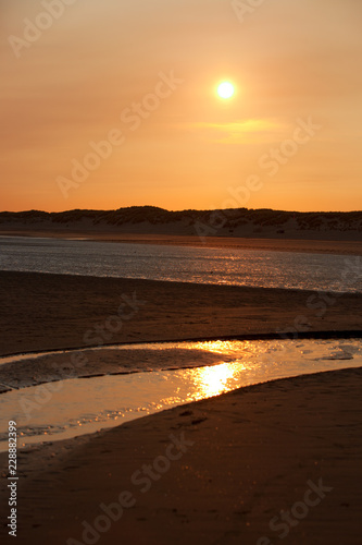 Sunset over Sandy Beach with rivulets of sea water reflecting the light