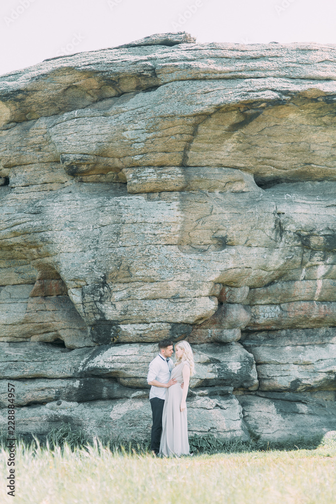 Weddings in the mountains by the rocks. The ceremony in the style of fine art. Summer walking photo shoot of newlyweds.