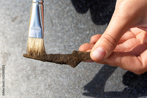Archeology: cleaning the rusty tip of an ancient arrow from the soil