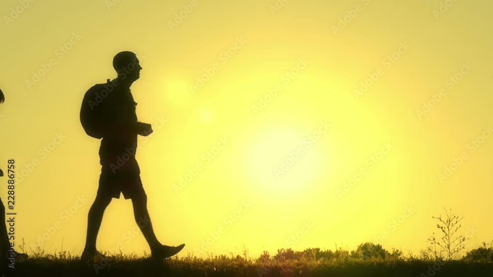 Silhouette of a happy family of tourists walking along the top of the mountain at sunset. Father and his two sons go camping. Silhouette of a happy family of tourists walking along the top of the mountain at sunset. Father and his two sons go camping.