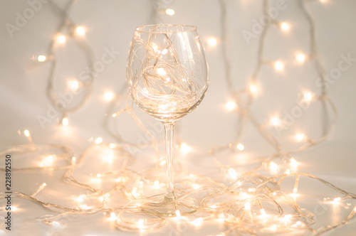 Wine glass with holiday lights inside on white background