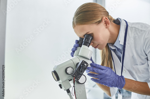 Full concentration. Side view portrait of female scientist in sterile gloves doing medical research. Copy space in right side photo