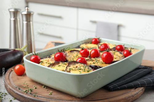 Baked eggplant with tomatoes and cheese in dishware on table against blurred background