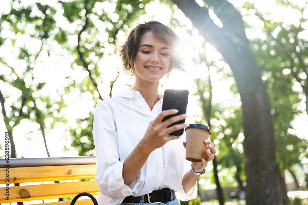 Beautiful young woman in earphones sitting outdoors Beautiful young woman in earphones sitting outdoors