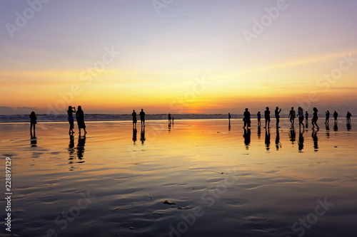 Silhouettes of people enjoying sunset in Seminyak beach, Kuta, Bali, Indonesia. photo