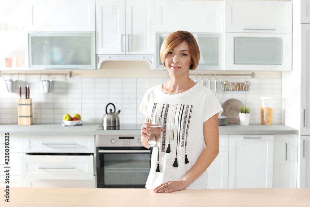 Woman holding glass with clean water in kitchen Woman holding glass with clean water in kitchen