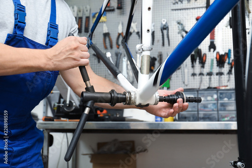 Professional mechanic repairing bicycle in modern workshop, closeup