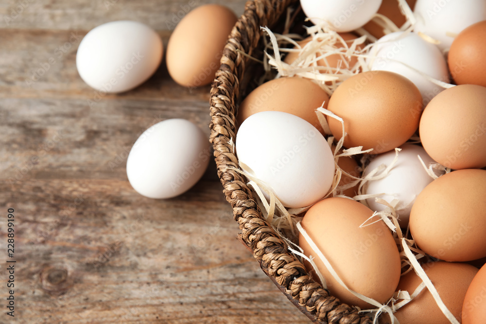 Basket with raw chicken eggs on wooden background Basket with raw chicken eggs on wooden background