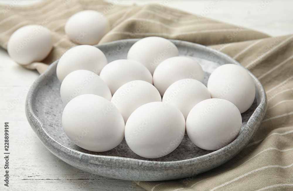 Plate with raw chicken eggs on wooden table Plate with raw chicken eggs on wooden table
