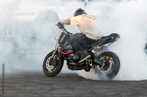 biker burning tire and creating smoke on bike in motion