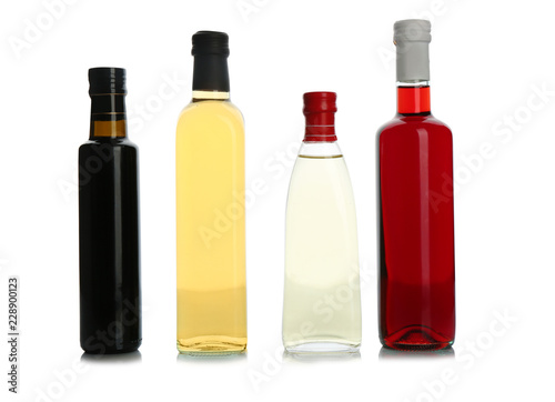 Glass bottles with different kinds of vinegar on white background