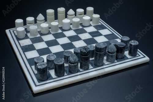 A game of chess with a modern black and white stone set of chess pieces