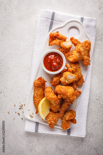 Fried Breaded chicken with tomato sauce on a white board, top view. photo