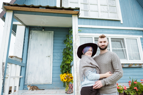 Young woman and man, family, sitting on porch of village house with pumpkins. © spaskov