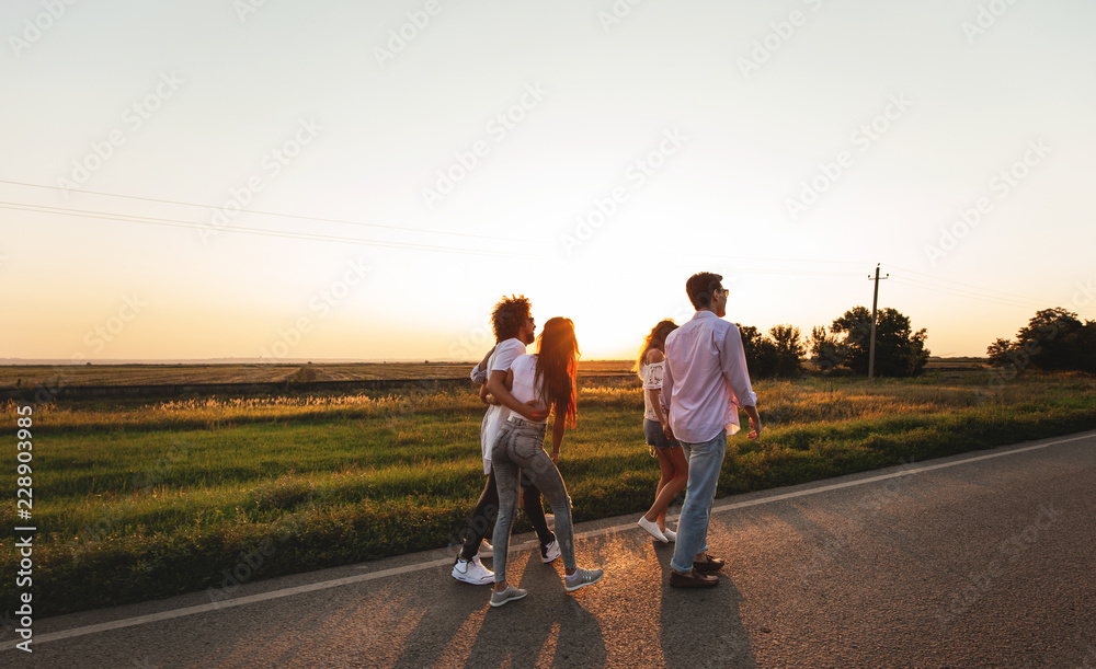 Company of happy young stylish guys walk along the road. on a sunny day Company of happy young stylish guys walk along the road. on a sunny day