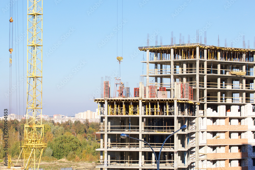 Tower cranes on the construction of a building with a frame of reinforced concrete.