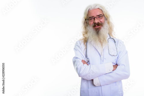 Studio shot of happy senior bearded man doctor smiling while wea photo