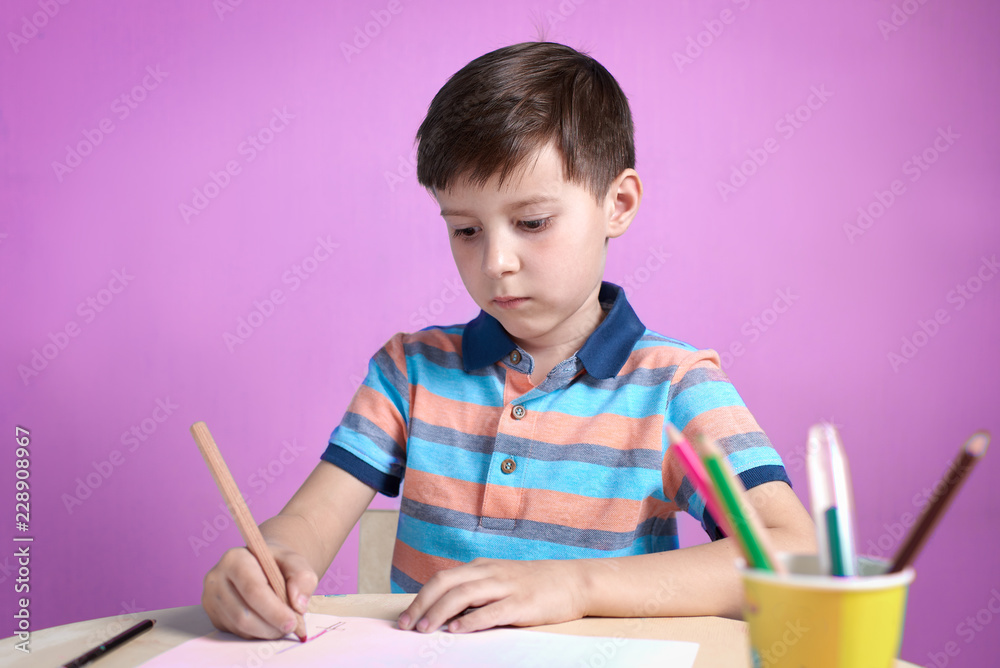 European boy carefully drawing with colorful pencils at home. European boy carefully drawing with colorful pencils at home.