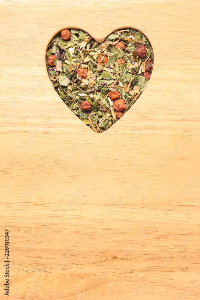 Dried herb leaves heart shaped on wooden surface Dried herb leaves heart shaped on wooden surface