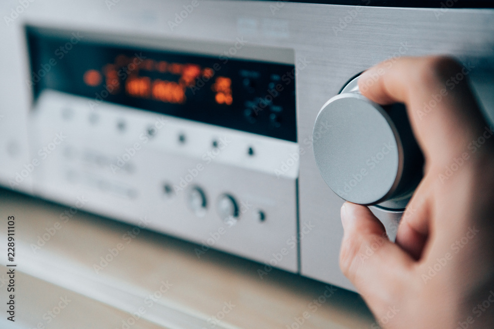 Fototapeta premium Mans hand rotating the Amplifier Volume regulator Adjusting the loudness