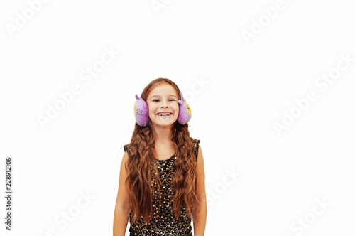 little girl with long hair in warm headphones is looking straight and smiling portrait