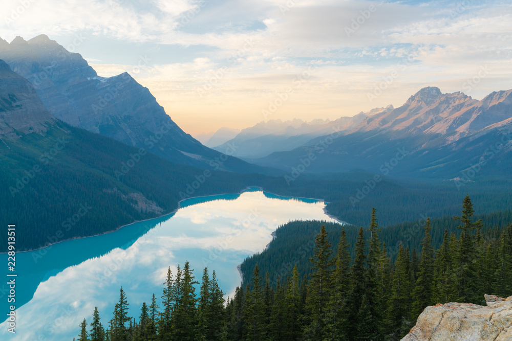 The orange glow of sunset over Peyto Lake in Banff National Park with a green forest
