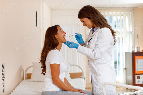 Young woman doctor takes a swab from the throat