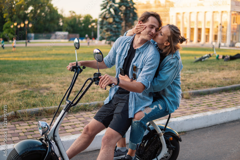 Obraz premium Lovely young couple driving electric bike during summer. Modern city dating and transportation