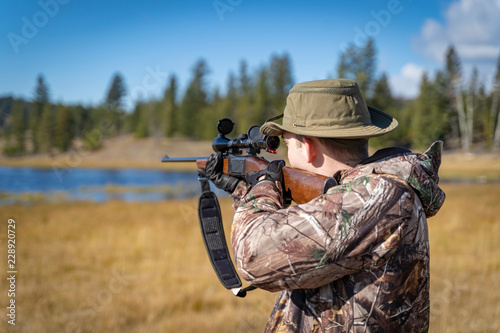A Hunter In Camouflage Aiming a Scope and Rifle