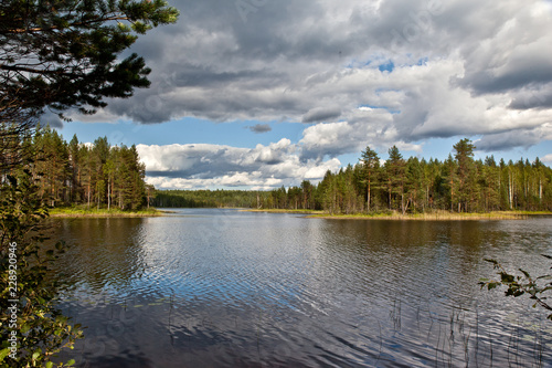 Beautiful volumetric clouds on a sunny day over a quiet forest lake