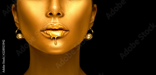 Gold paint drips from the sexy lips  golden liquid drops on beautiful model girl s mouth  creative abstract makeup. Beauty woman face isolated on black background