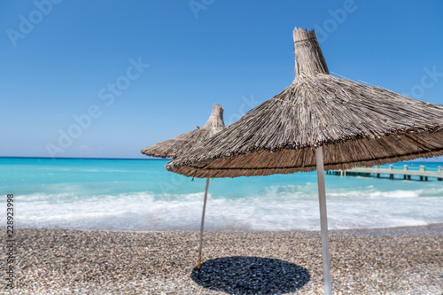 tropical umbrellas on a island beach. Blue ocean on background. Tourism travel concept