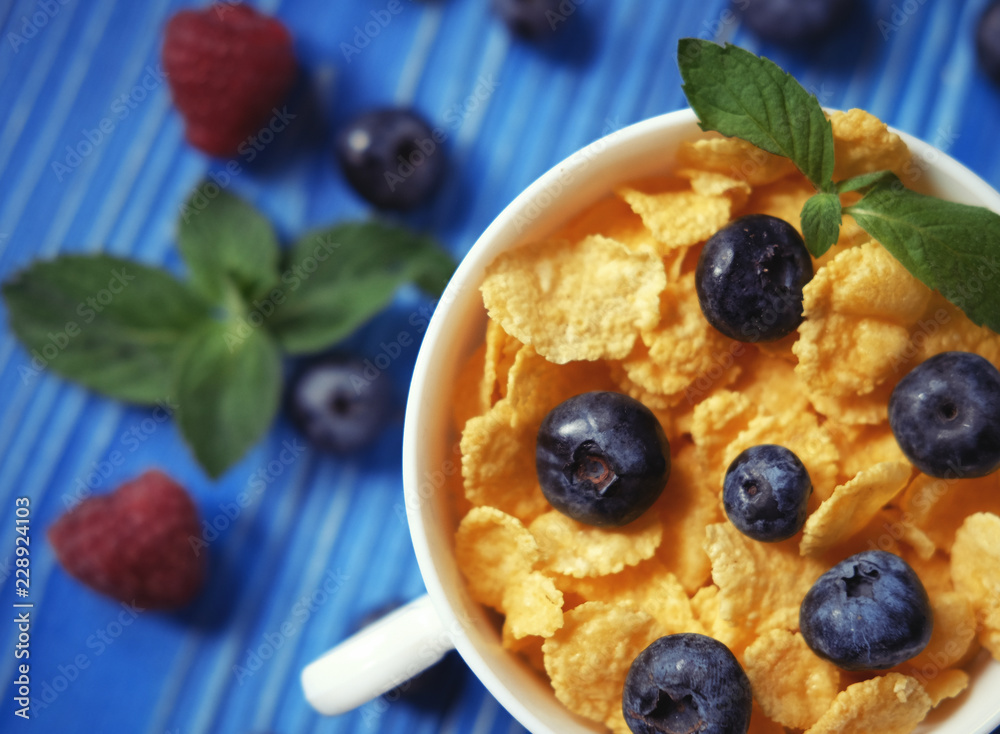 Healthy eating, food and diet concept - Cornflakes with berries raspberries and blueberries on blue wooden background. Top view. Healthy eating, food and diet concept - Cornflakes with berries raspberries and blueberries on blue wooden background. Top view.